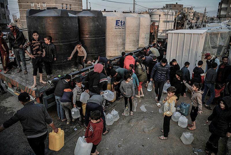 Saldırılardan kaçarak Gazze'nin Refah kentindeki çadırlarda yaşayan çocuklar, hayır kurumlarının dağıttı sudan alabilmek için sıraya giriyor.
