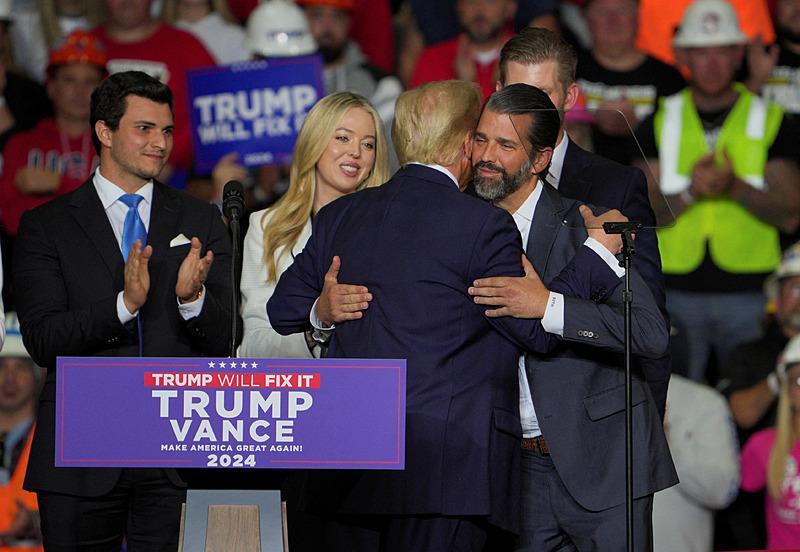 Cumhuriyetçi başkan adayı ve eski ABD Başkanı Donald Trump, Kasım ayında ABD'nin Pennsylvania eyaletinin Pittsburgh kentinde düzenlediği kampanya mitinginde Eric Trump, Michael Boulos ve Tiffany Trump bakarken Donald Trump Jr'ı kucaklıyor, Reuters